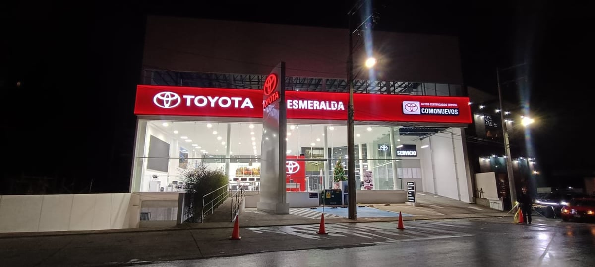 Nighttime view of a Toyota dealership storefront with illuminated red signage and display windows