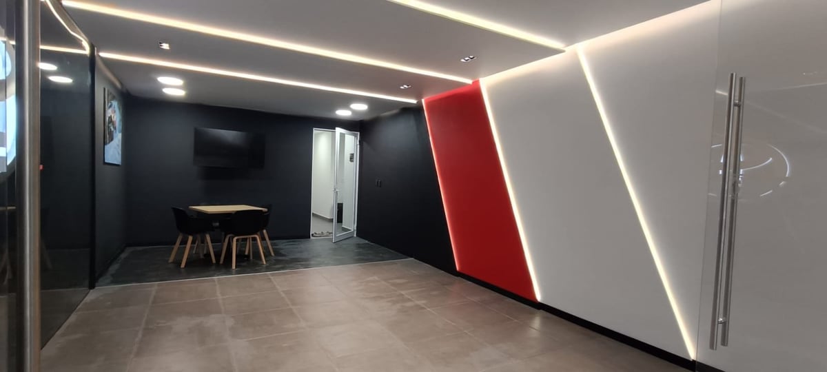 Modern office hallway with minimalist design, concrete floor, geometric red and white wall panels, and linear ceiling lights